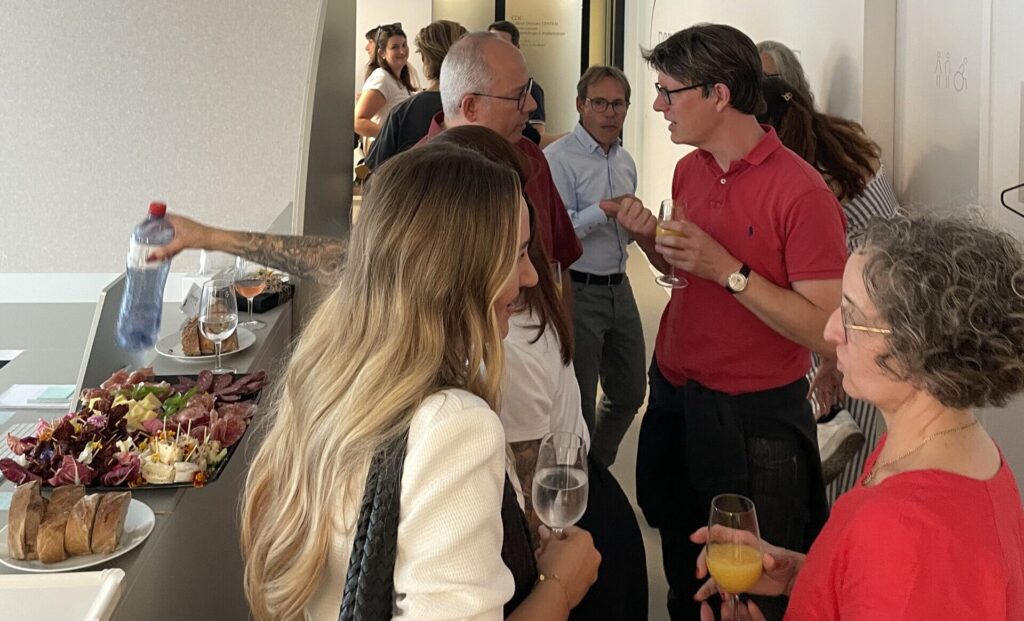 Viele Besuchende im Eingangsbereich der Espace Métabolique. Bedienen sich am Buffet oder halten Gläser mit Wasser oder Orangensaft