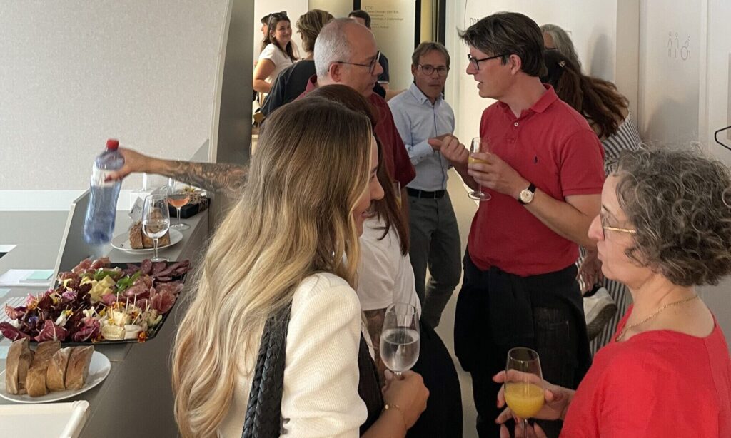 Viele Besuchende im Eingangsbereich der Espace Métabolique. Bedienen sich am Buffet oder halten Gläser mit Wasser oder Orangensaft